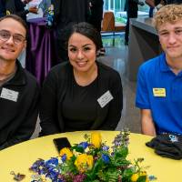 Three event guests sitting together and smiling at camera